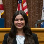 Molly Lucia in front of the bench at Nova Southeaster University Shepard Broad College of Law.