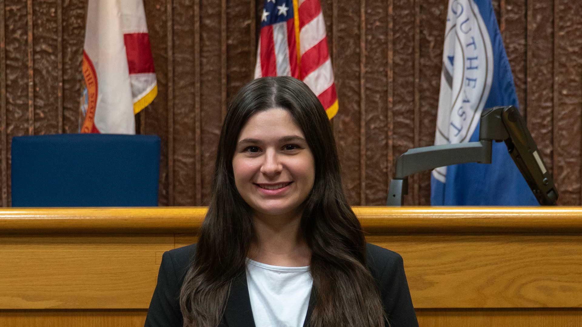 Molly Lucia in front of the bench at Nova Southeaster University Shepard Broad College of Law.